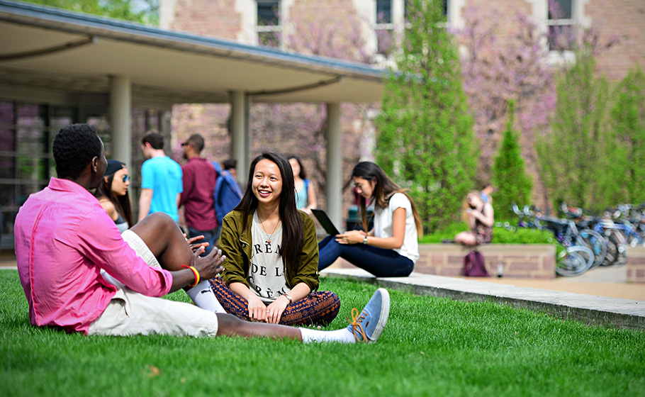 students sitting on grass by Olin library