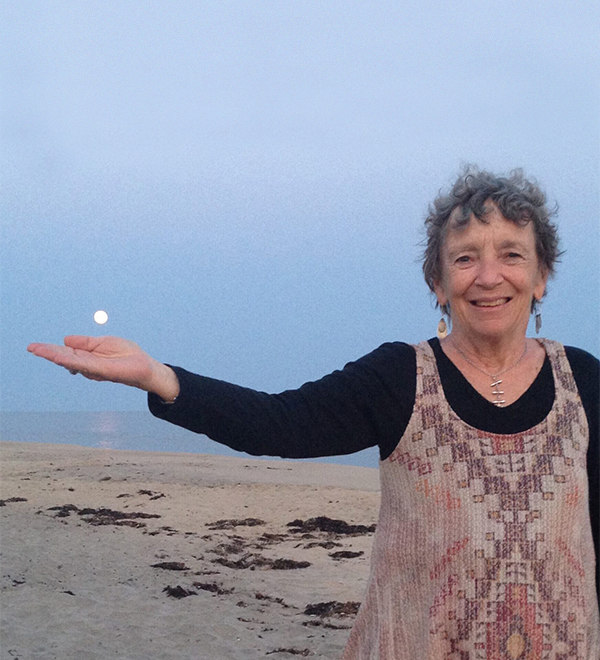 乌苏拉Goodenough站在海滩上,伸出她的手在满月的夜晚